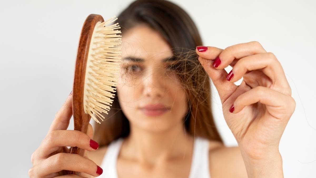 Donna osserva i capelli rimasti sulla spazzola durante la caduta stagionale
